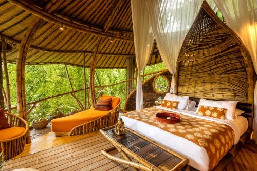 ein Schlafzimmer in einem Zelt mit einem Bett und einem Tisch in der Unterkunft Bambu Indah in Ubud