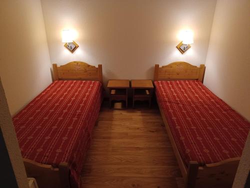 - 2 lits dans une petite chambre avec des couvertures rouges dans l'établissement Appartement spacieux à 300m des pistes et commerces, balcon sud, parking. Confortable - FR-1-618-23, à Albiez-Montrond
