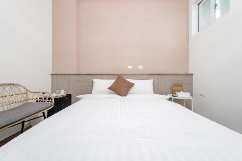 a bedroom with a large white bed and a chair at Taitung Yu Krung Smart Stay in Taitung City