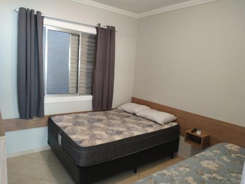 un dormitorio con una cama y una ventana en Kitnet Asturias 51B no Ed. Guariatã, próximo a praia das Astúrias em Guarujá, en Guarujá