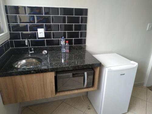 encimera con fregadero y nevera en Kitnet Asturias 51B no Ed. Guariatã, próximo a praia das Astúrias em Guarujá, en Guarujá