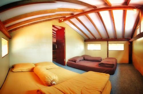 two beds in a room with a large ceiling at Avrila Ijen Guest House in Licin