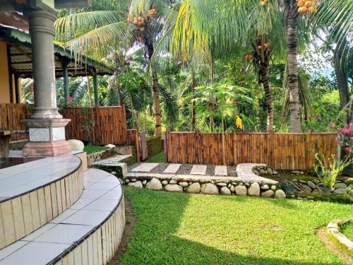 a backyard with a wooden fence and a garden at Sumatra Cheeky Monkeys in Bukit Lawang