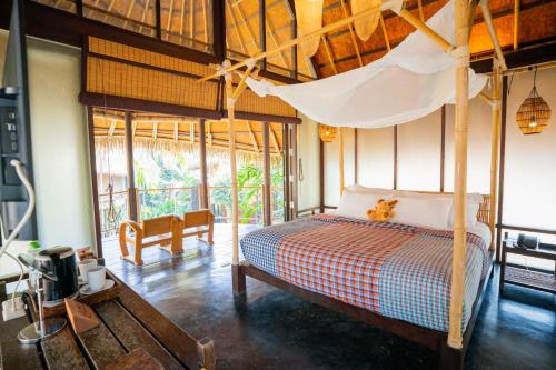 a bedroom with a bed with a mosquito net at LA A NATU Pranburi in Sam Roi Yot