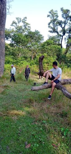 two men sitting on a tree log in a field at Crocodile Safari Camp in Chitwan