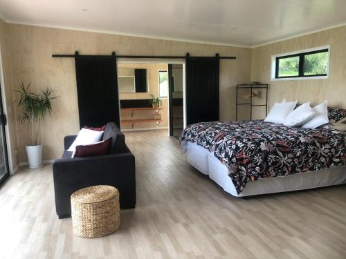 a bedroom with a bed and a couch and a chair at Whakaipo Bay Cabin Retreat Taupo in Taupo