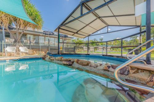 a swimming pool with a patio and a building at BIG4 Lake Maraboon Holiday Village in Gindie
