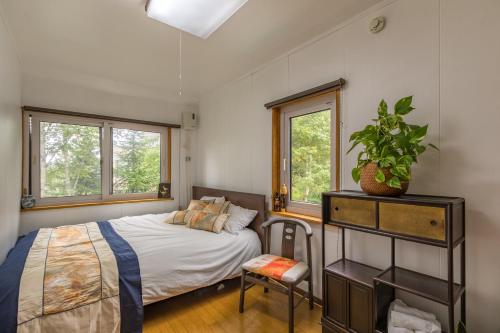sypialnia z łóżkiem i krzesłem oraz 2 oknami w obiekcie Freeride Backpackers Lodge Niseko w mieście Niseko