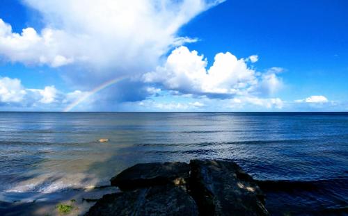 a rainbow over the ocean with rocks in the water at Piejūras apartamenti STEAMER in Roja
