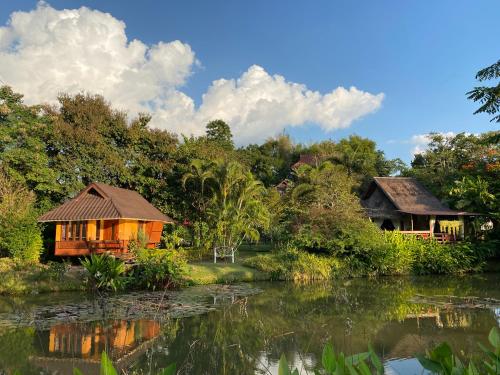 a couple of houses next to a body of water at Pura Vida Pai Resort in Pai