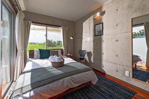 a bedroom with a large bed with a large window at LEO Resort Sunayama in Miyako Island