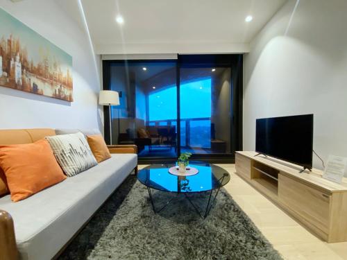 a living room with a couch and a television at Box Hill Central Sky One Apartment in Box Hill