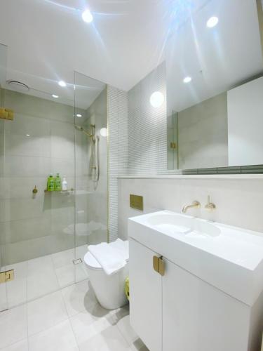 a bathroom with a sink and a toilet and a mirror at Box Hill Central Sky One Apartment in Box Hill