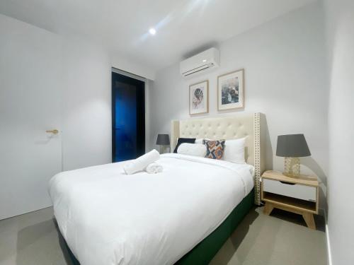 a bedroom with a large white bed and a lamp at Box Hill Central Sky One Apartment in Box Hill