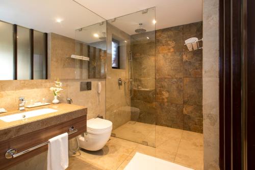 a bathroom with a shower and a toilet and a sink at Nanu Beach Resort & Spa in Betalbatim
