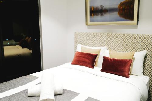 a bedroom with a white bed with two red pillows at Box Hill Central Sky One Apartment in Box Hill