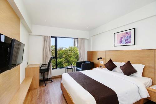 a hotel room with a bed and a television at Hotel Mumbai House Ghansoli, Navi Mumbai in Navi Mumbai