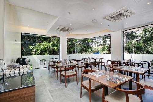 een restaurant met tafels en stoelen en grote ramen bij Hotel Mumbai House Ghansoli, Navi Mumbai in Navi Mumbai
