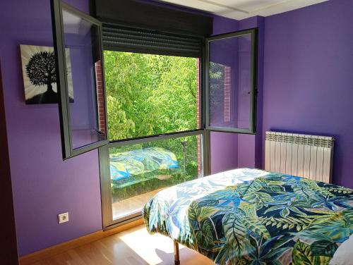 Dormitorio púrpura con cama y ventana en La Terraza de Zahara, en Pamplona