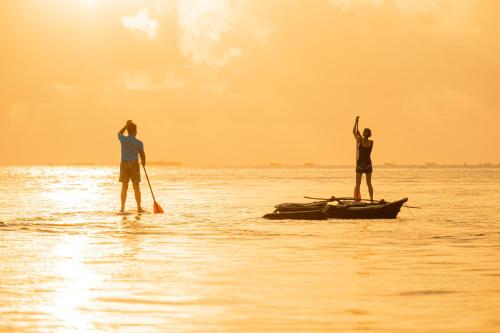 two people are standing on a boat in the water at Chole Mjini Treehouses Lodge in Utende