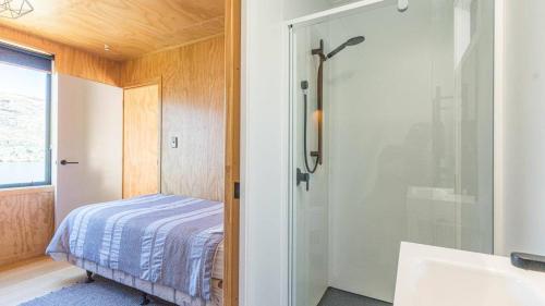 a bedroom with a bed and a shower and a sink at Picture Perfect - Queenstown Holiday Home in Queenstown