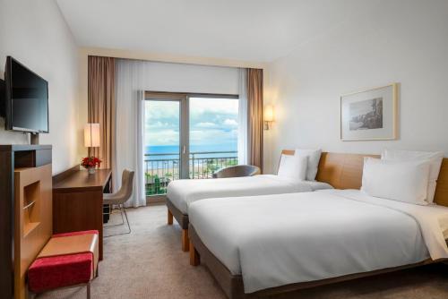 a hotel room with two beds and a television at Novotel Trabzon in Trabzon