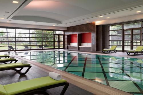 a large swimming pool with green chairs and windows at Novotel Trabzon in Trabzon