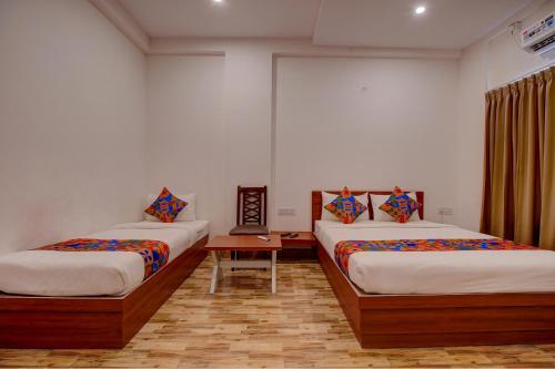 a room with two beds and a table in it at FabHotel Sri Udupi Park in Bengaluru