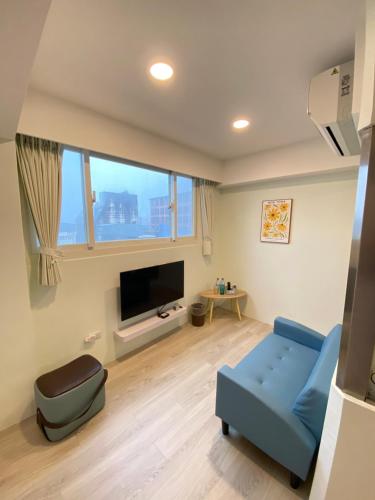a living room with a blue couch and a tv at 小窩旅店-羅東夜巿店 in Luodong