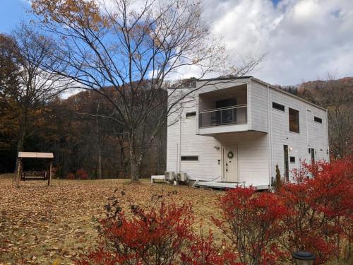 a small white building with a balcony on a field at Polar Haus MinamiKaruisawa1 - Vacation STAY 88000v in Karuizawa