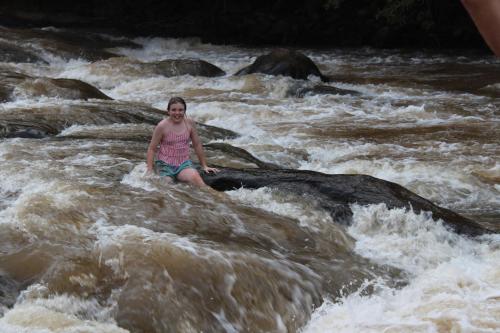 a woman sitting on a rock in a river at Lions Rock Rapids - Lodge in Hazyview