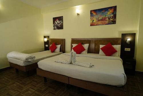 2 Betten in einem Hotelzimmer mit roten und weißen Kissen in der Unterkunft Hotel Gaurab Near Paltan Bazaar in Dehradun