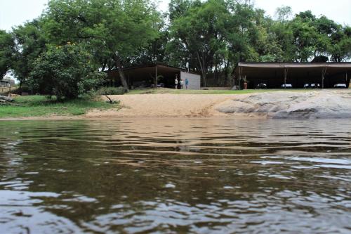 a body of water with a building in the background at Lions Rock Rapids - Lodge in Hazyview