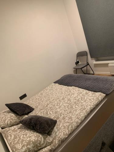 uma cama com duas almofadas e uma cadeira num quarto em New Ozas flat em Vilnius