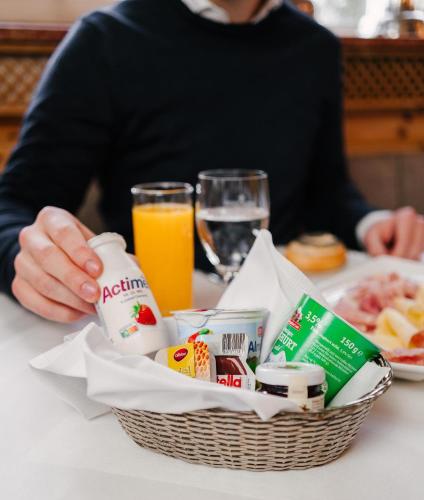 a person sitting at a table with a basket of food and orange juice at Schlosshotel Grünwald in Grünwald