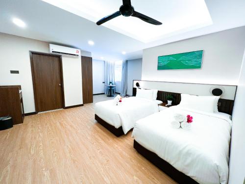 a hotel room with two beds and a ceiling fan at Villea Port Dickson in Port Dickson