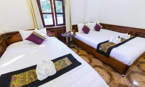 a room with two beds with towels on them at Moon's house LuangPrabang in Luang Prabang