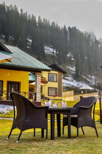 two chairs and a table in front of a house at Arco Hotels & Resorts sonamarg in Sonāmarg