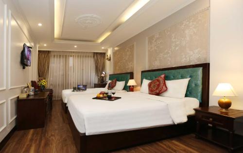 a hotel room with two beds and two tables at Golden Sail Hotel & Spa in Hanoi
