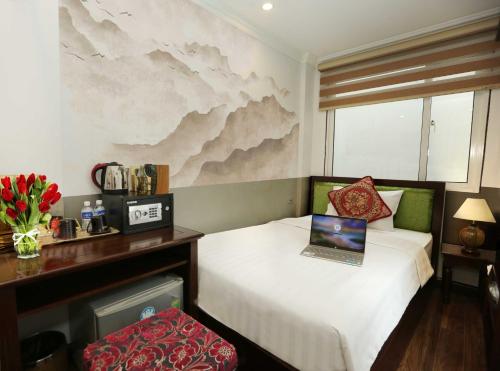 a bedroom with a bed with a laptop on it at Golden Sail Hotel & Spa in Hanoi