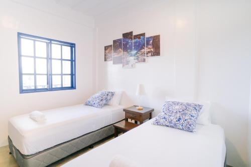 two white beds in a room with a window at BlueWoods Seaside Resort in Dauis