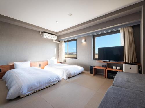 a hotel room with two beds and a flat screen tv at EN HOTEL Kyoto in Kyoto