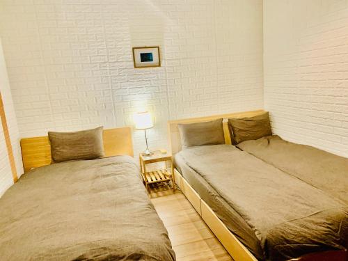 - 2 lits installés l'un à côté de l'autre dans une chambre dans l'établissement YokohamaKannai HouseBar, à Yokohama