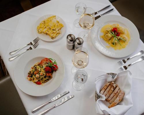 a white table with plates of food and glasses of wine at Schlosshotel Grünwald in Grünwald