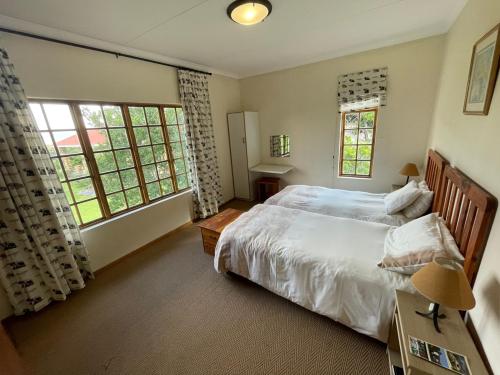 1 dormitorio con 1 cama grande y 2 ventanas en Malutizicht Lodge en Brandwater