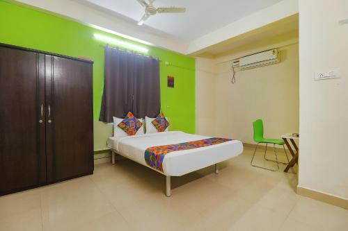 a bedroom with a bed and a green wall at FabHotel Broholic in Hyderabad