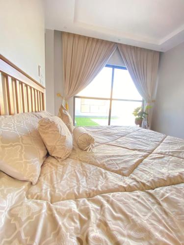 ein großes Bett in einem Schlafzimmer mit Fenster in der Unterkunft شاليه ريفان in Umm Lajj