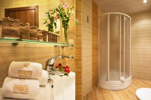 a bathroom with a shower and a sink with towels at Uniqato Hotel in Stara Zagora