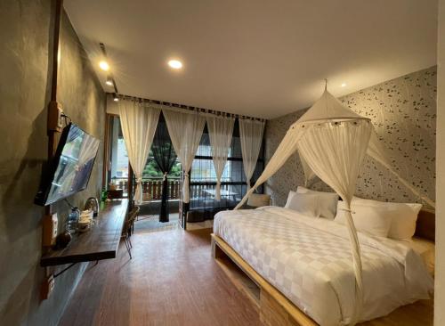 een slaapkamer met een wit bed en een televisie bij Hotel Kalang Ulu in Berastagi