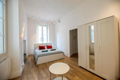 Coeur de ville, magnifique appartement + parking في بو: غرفة نوم بيضاء مع سرير وطاولة